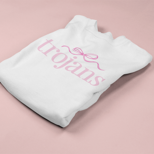 White sweatshirt with 'trojans' text and pink bow on a pink background